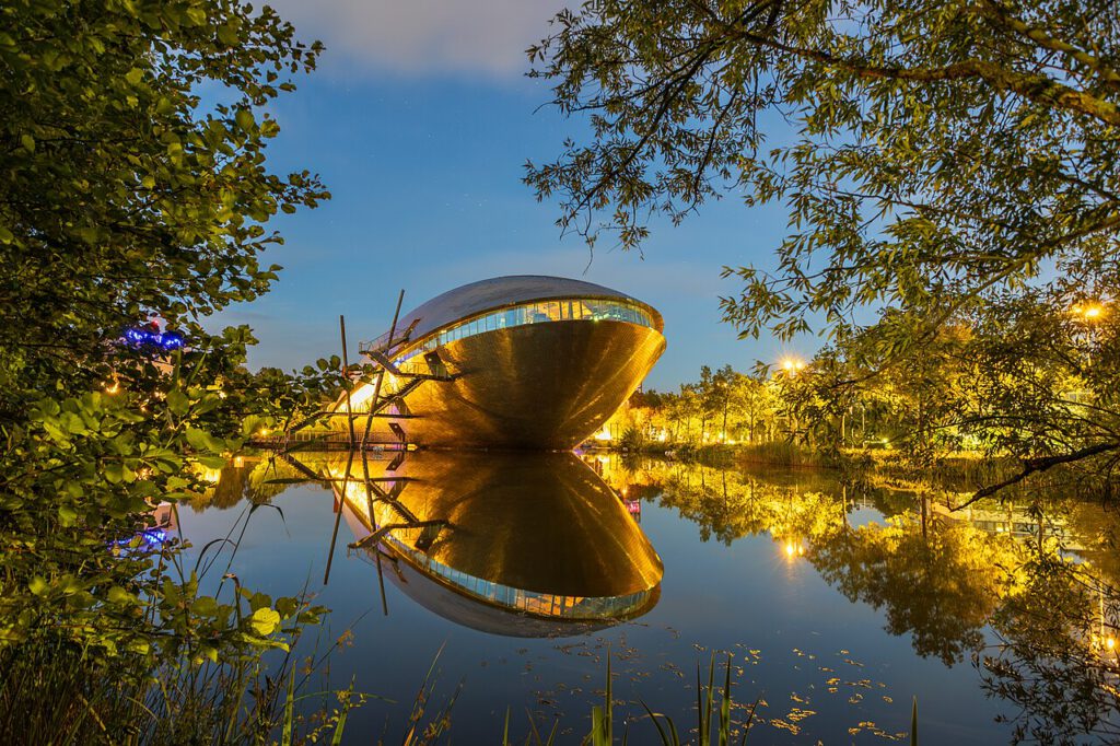 Das Universum Science Scenter in Bremen. Aufgenommen zur blauen Stunde vom gegenüberliegenden Seeufer. Die Architektur des Gebäudes erinnert an einen gestrandeten Wal. Das Gebäude selbst spiegelt sich im See.