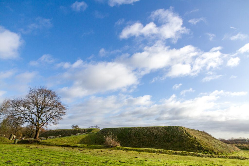 Die wiedererrichtete Schanze 14 des Danewerks. Zu sehen ist ein abgeflachtes pyramidenförmiges Bauwerk aus mit Gras bewachsender Erde. Links führt eine Rampe in die Schanze.