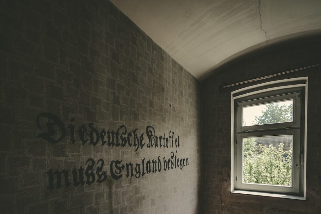 Blick in eine Zelle mit der an die Wand geschriebenen Parole "Die deutsche Kartoffel muss England besiegen".