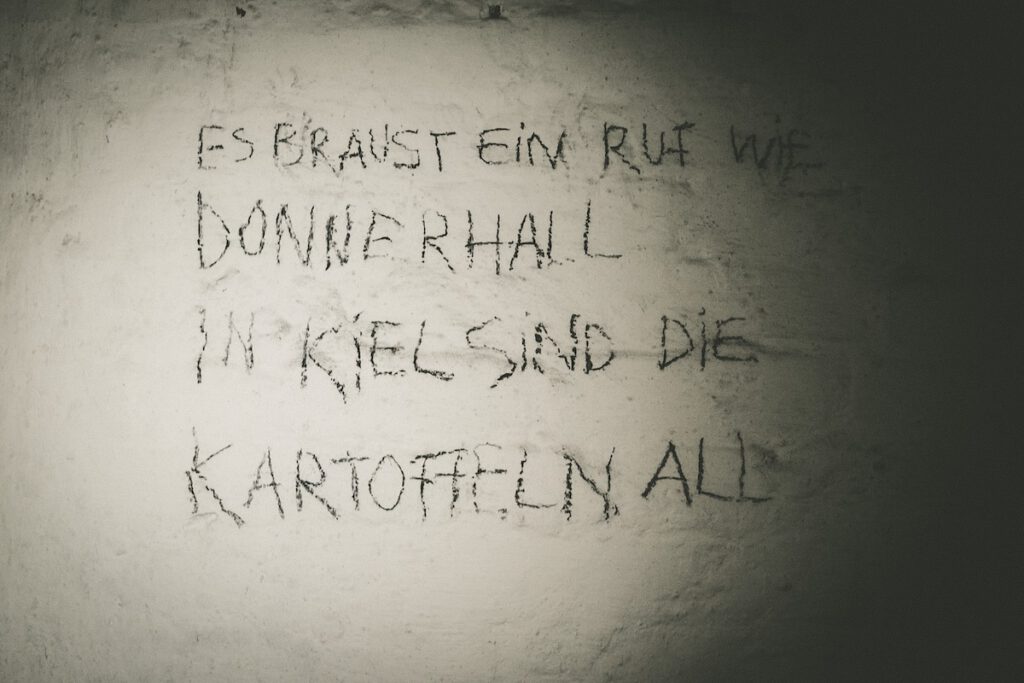 Eine weitere, für das Theaterstück  an eine Wand geschriebene Parole. Dort steht erneut "Es braust ein Ruf wie Donnerhall, in Kiel sind die Kartoffeln all" zu lesen.