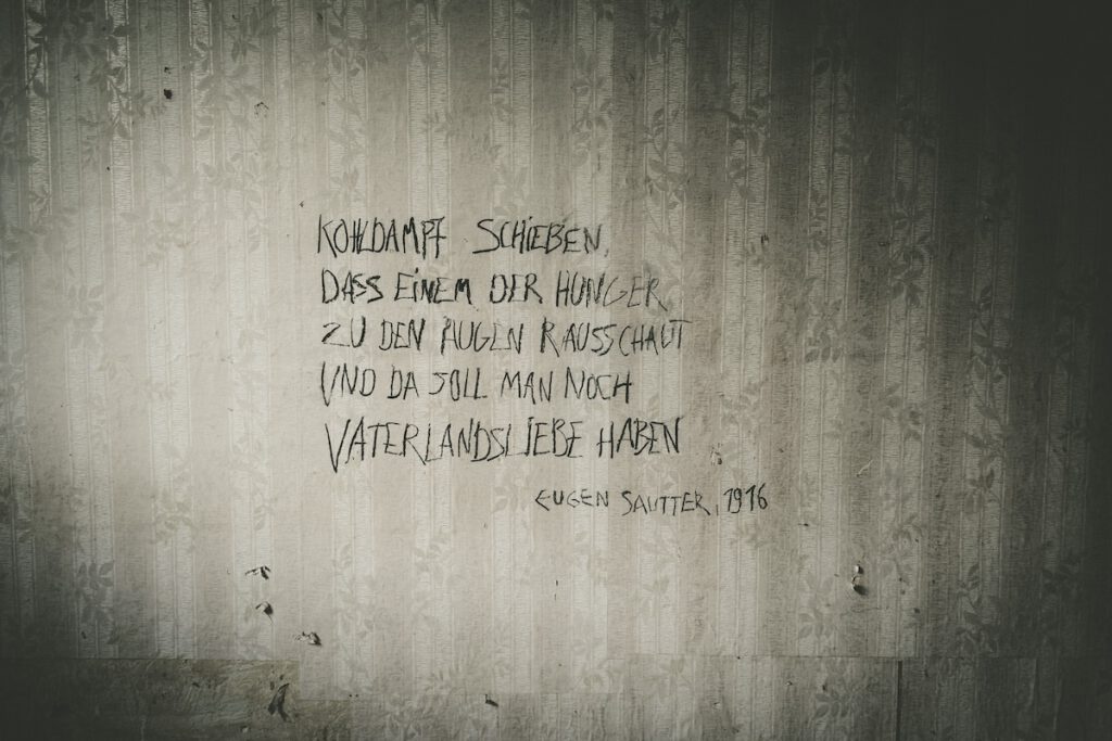 Eine weitere, für das Theaterstück  an eine Wand geschriebene Parole. Dort steht" Kohldampf schieen, dass einem der Hunger zu den Augen rausschaut und da soll man noch Vaterlandsliebe haben, Eugen Sauter, 1916" zu lesen.