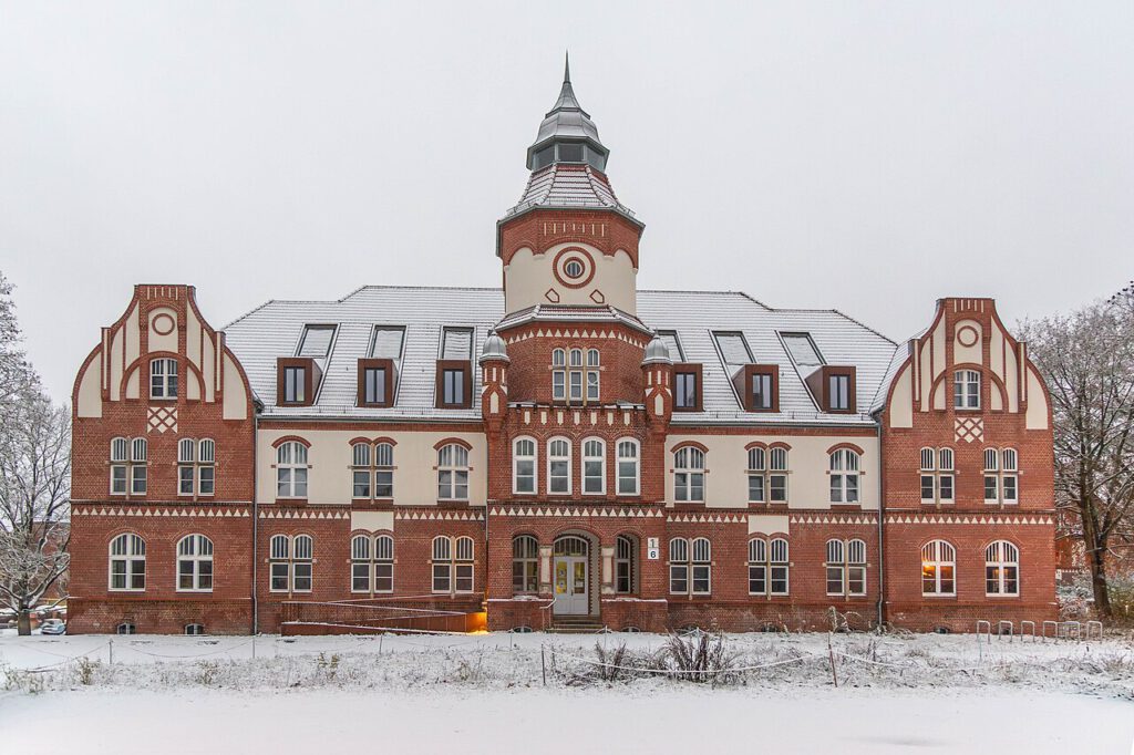 Das ehemalige Verwaltungsgebäude des Anscharkrankenhuases hat mit seinen Türmen eine schlossartige Anmutung. Zu sehen ist das Gebäude mit seinen vielen Zierelementen.