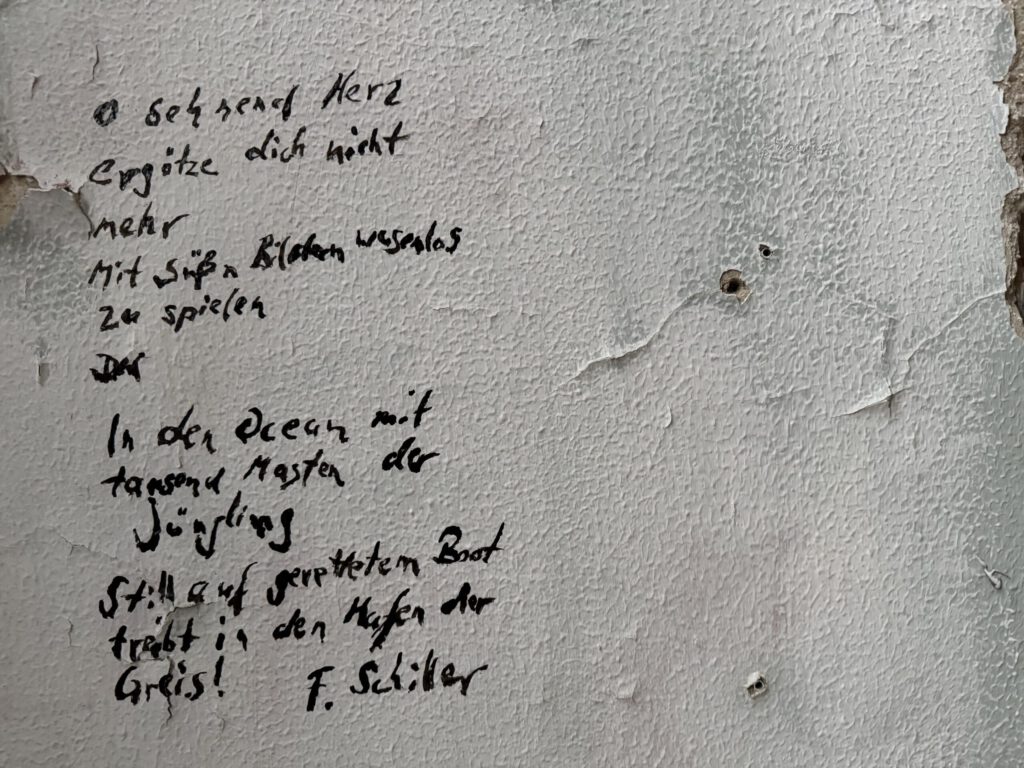 Bild einer verfallenen Wand. hat jemand mit einem schwarzen Stift ein Gedicht von Schiller geschrieben