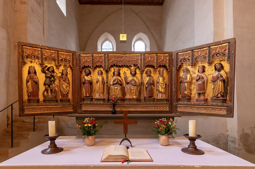 Der dreiteilige Flügelaltar im Kloster Drübeck, eine spätgotische Schnitzarbeit. In Halbreliefs dargestellt sind die Krönung Mariens durch Christus, flankiert von männlichen und weiblichen Heiligen, die kunstvolle Detailarbeit und religiöse Symbolik der Epoche widerspiegelnd