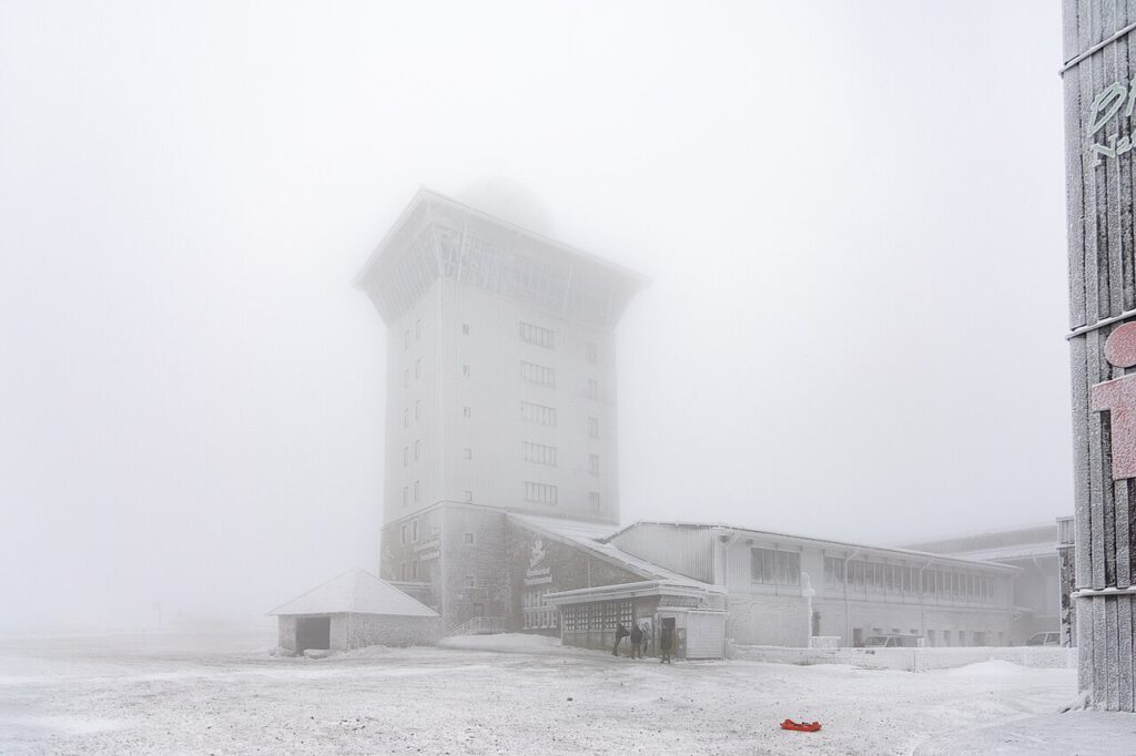 Das Brockenhotel umhüllt von dichtem Eisnebel. Die Konturen des Gebäudes wirken verschwommen, während die frostige Atmosphäre die Szenerie geheimnisvoll und unwirtlich erscheinen lässt.