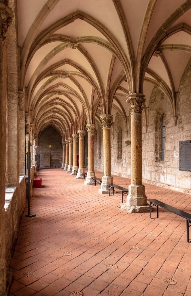 Der Kreuzgang des Klosters Walkenried mit einem doppelten gotischen Gewölbe, das von einer eleganten Säulenreihe getragen wird. Die feine Steinmetzarbeit und die harmonische Architektur schaffen eine beeindruckende, historische Atmosphäre.