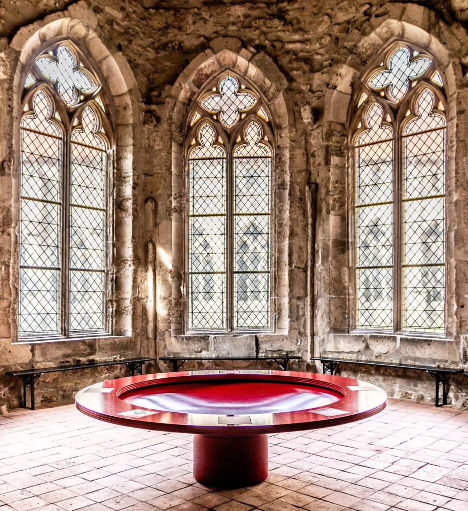 Das historische Brunnenhaus des Klosters Walkenried, kombiniert mit einem modernen roten Brunnen in der Mitte. Die Kontraste zwischen der alten Architektur und dem zeitgenössischen Design schaffen eine faszinierende Verbindung von Vergangenheit und Gegenwart.