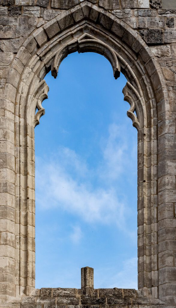 Detailaufnahme eines gotischen Fensters in der Ruine des Klosters Walkenried. Die filigranen Streben des Fensters sind herausgebrochen, was die Spuren der Zeit und den Verfall der historischen Bausubstanz eindrucksvoll zeigt.