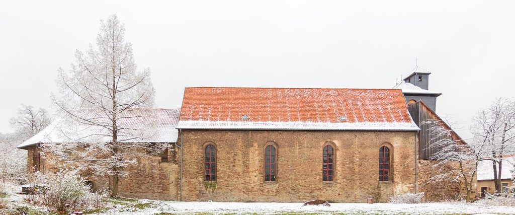 Außenaufnahme des Klosters Ilsenburg im Schnee. Die historische Klosterarchitektur ist von einer dünnen Schneedecke bedeckt, die der Szenerie eine ruhige und winterliche Atmosphäre verleiht.