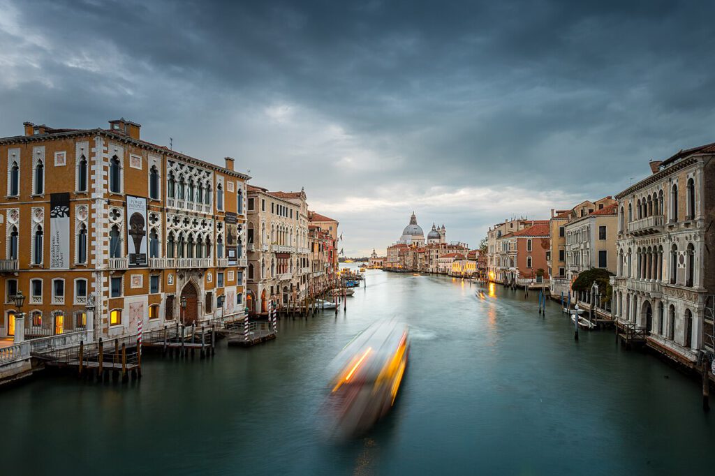 Venedig Kanal mit historischen Gebäuden und einem vorbeifahrenden Boot unter einem bewölkten Himmel, ideal für Reisefotografie und Stadtansichten.